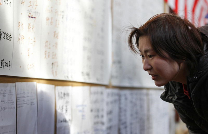 Một người đang tìm danh sách những người sống sót ở một trung tâm sơ tán ở tỉnh Iwate. Ảnh: Reuters.