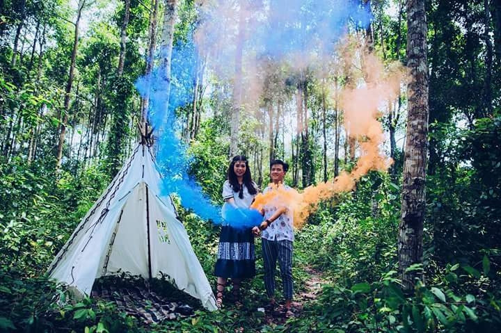 Hai bạn trẻ đang chụp ảnh đôi phong cách cắm trại với pháo màu