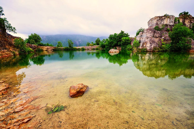 Vách đá, cột đá núi Tà Pạ in bóng xuống đáy hồ trong xanh