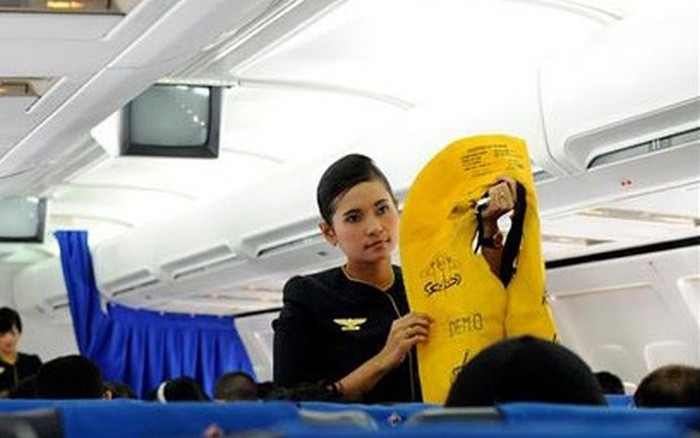 Tiếp viên hàng không đang hướng dẫn an toàn bay cho hành khách.