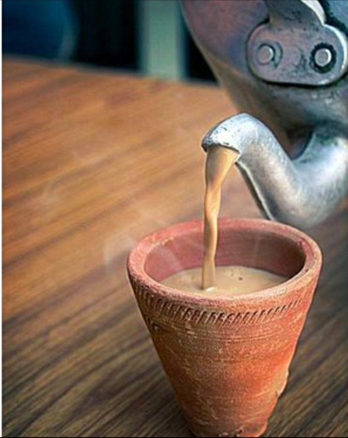 Masala chai nóng hổi đang được rót ra ly gốm theo đúng kiểu truyền thống