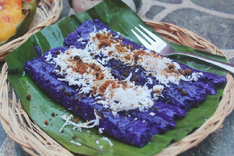 Puto Bumbong được phết bơ lên trên kèm theo một lớp dừa tươi nạo và đường muscovado.